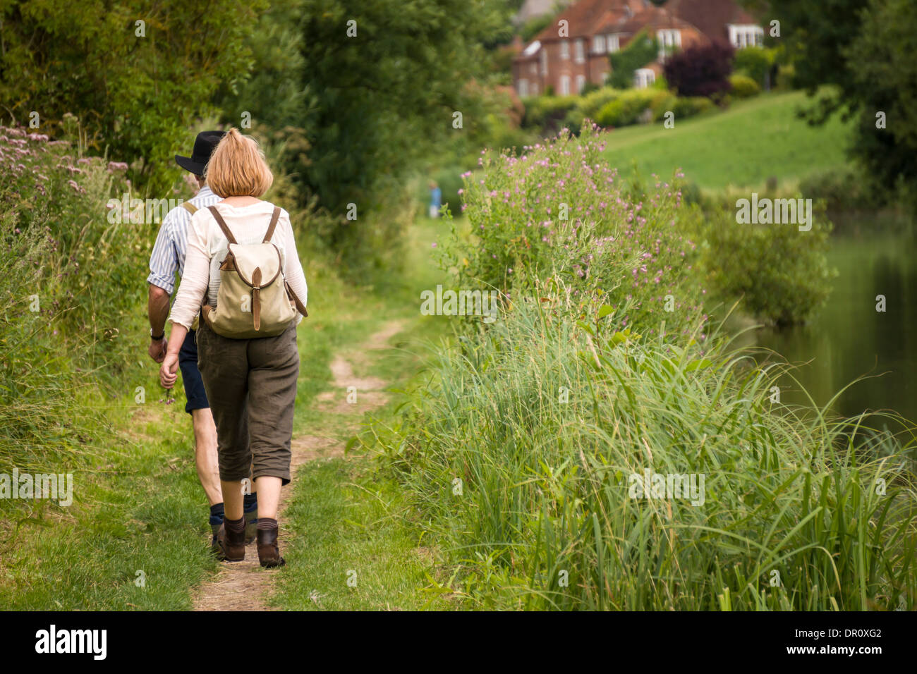 Due escursionisti a piedi lungo un sentiero sul canale in Berkshire. Foto Stock