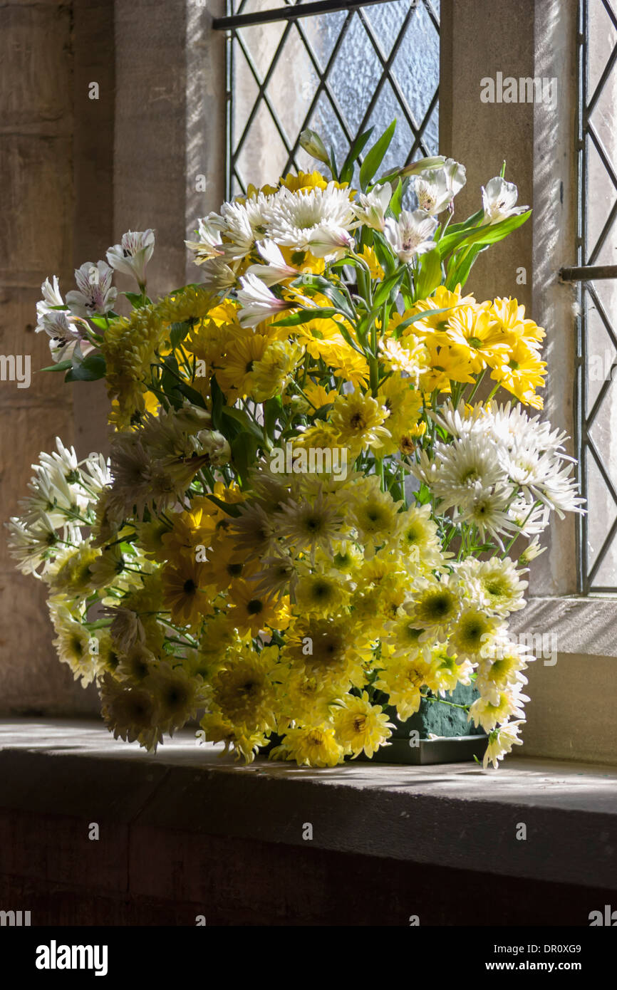 Un soleggiato la finestra della chiesa con fiori in Cotswolds. Foto Stock