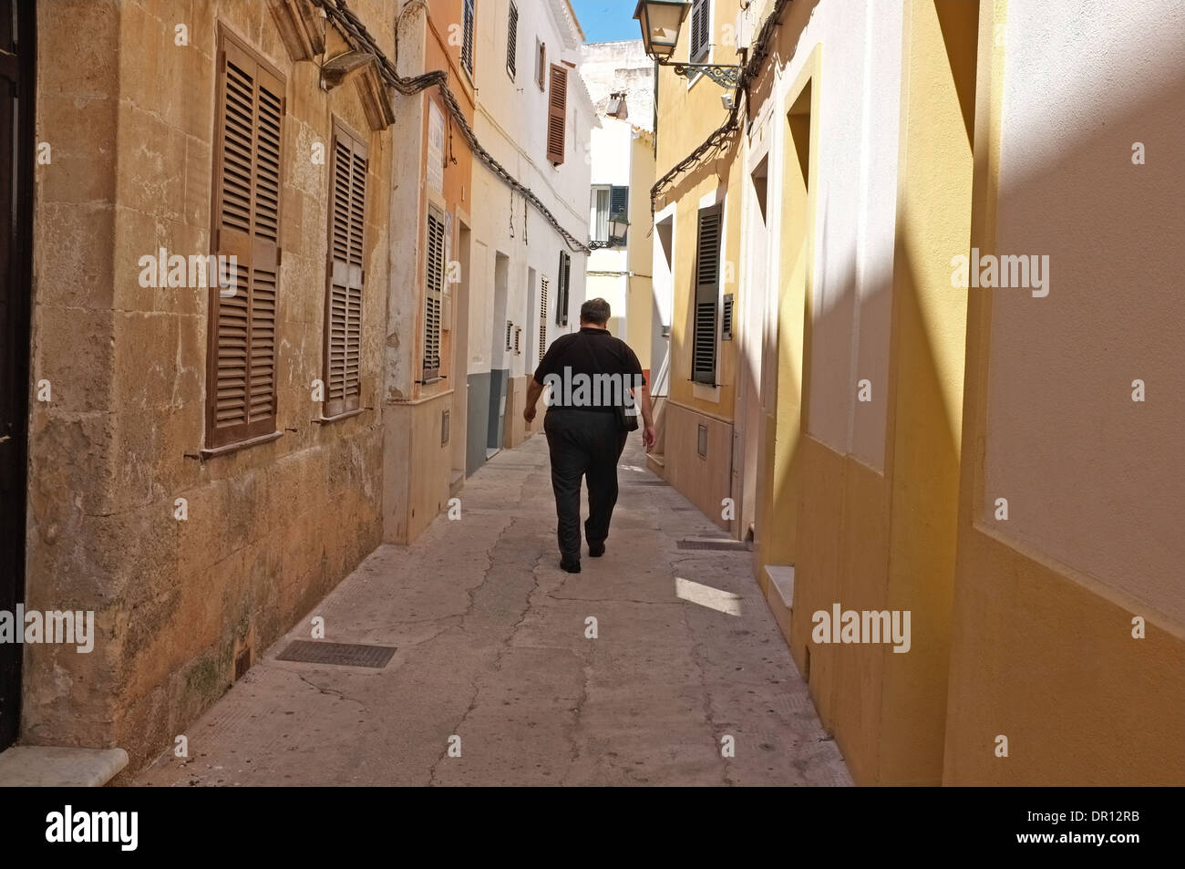 Un uomo cammina giù per una strada posteriore in Ciuta Della, Menorca. Foto Stock