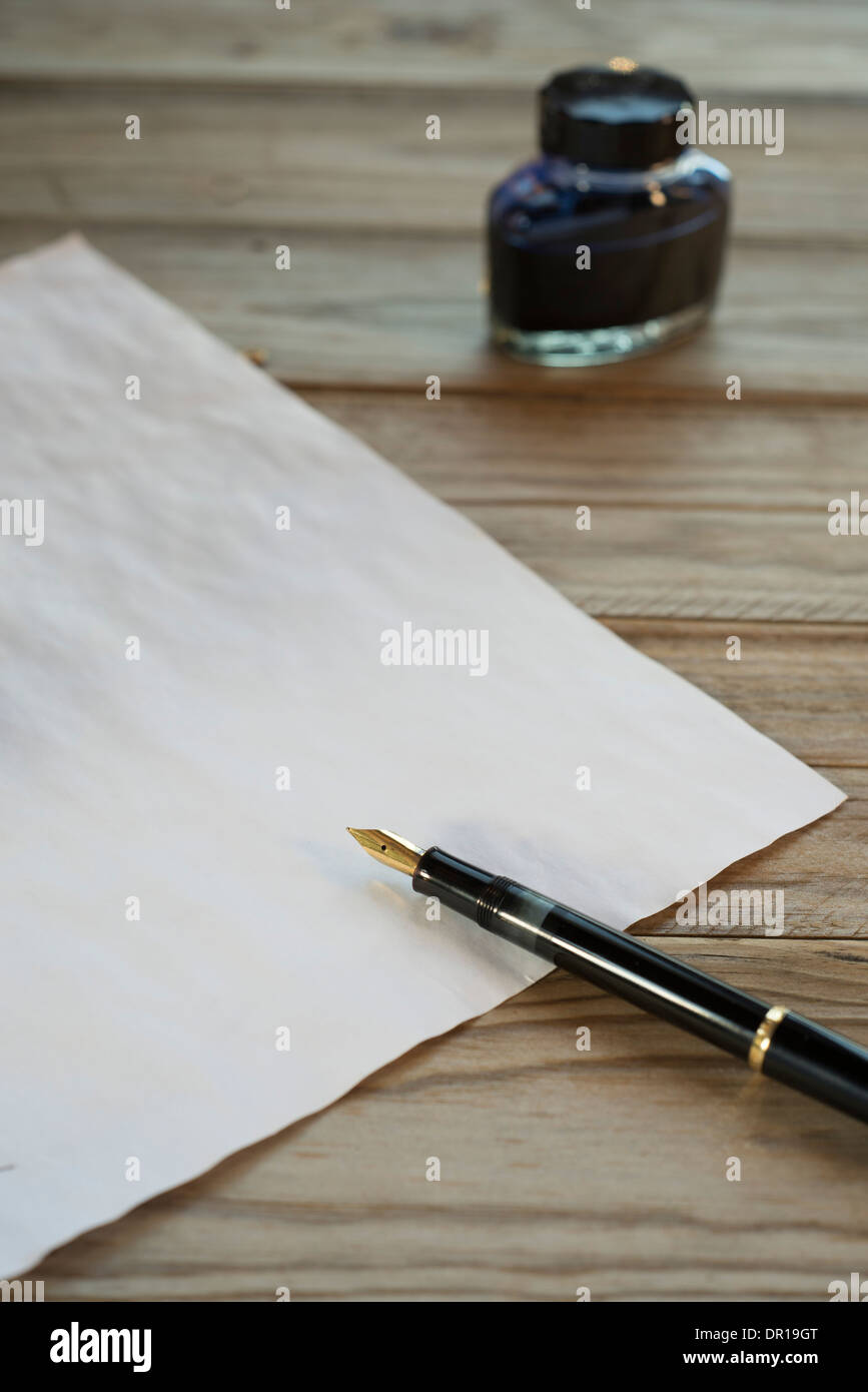 Penna stilografica, inchiostro e del foglio di carta su una tavola di legno Foto Stock