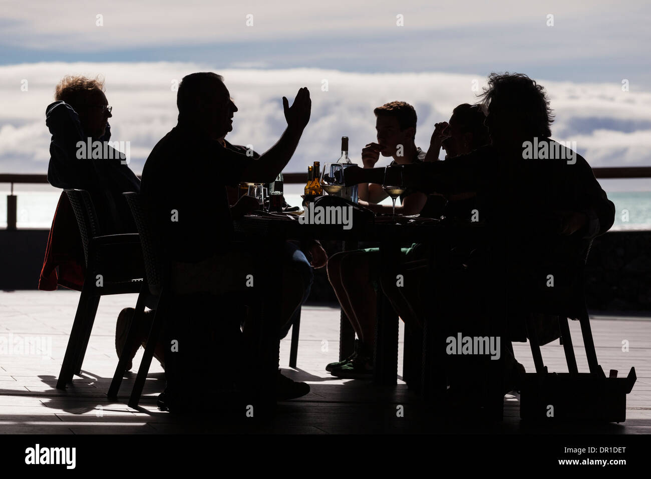 Silhouette di un gruppo di persone di mangiare il pranzo in un ambiente all'aperto a Fuencaliente, La Palma, Isole Canarie, Spagna. Foto Stock
