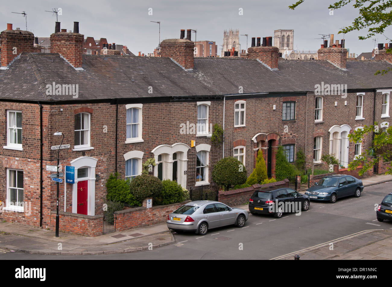 Vista alta su fila di piccole case a schiera vittoriane in mattoni rossi (cottage) su Victor Street (Minster Beyond) - York, Yorkshire, Inghilterra, Regno Unito Foto Stock