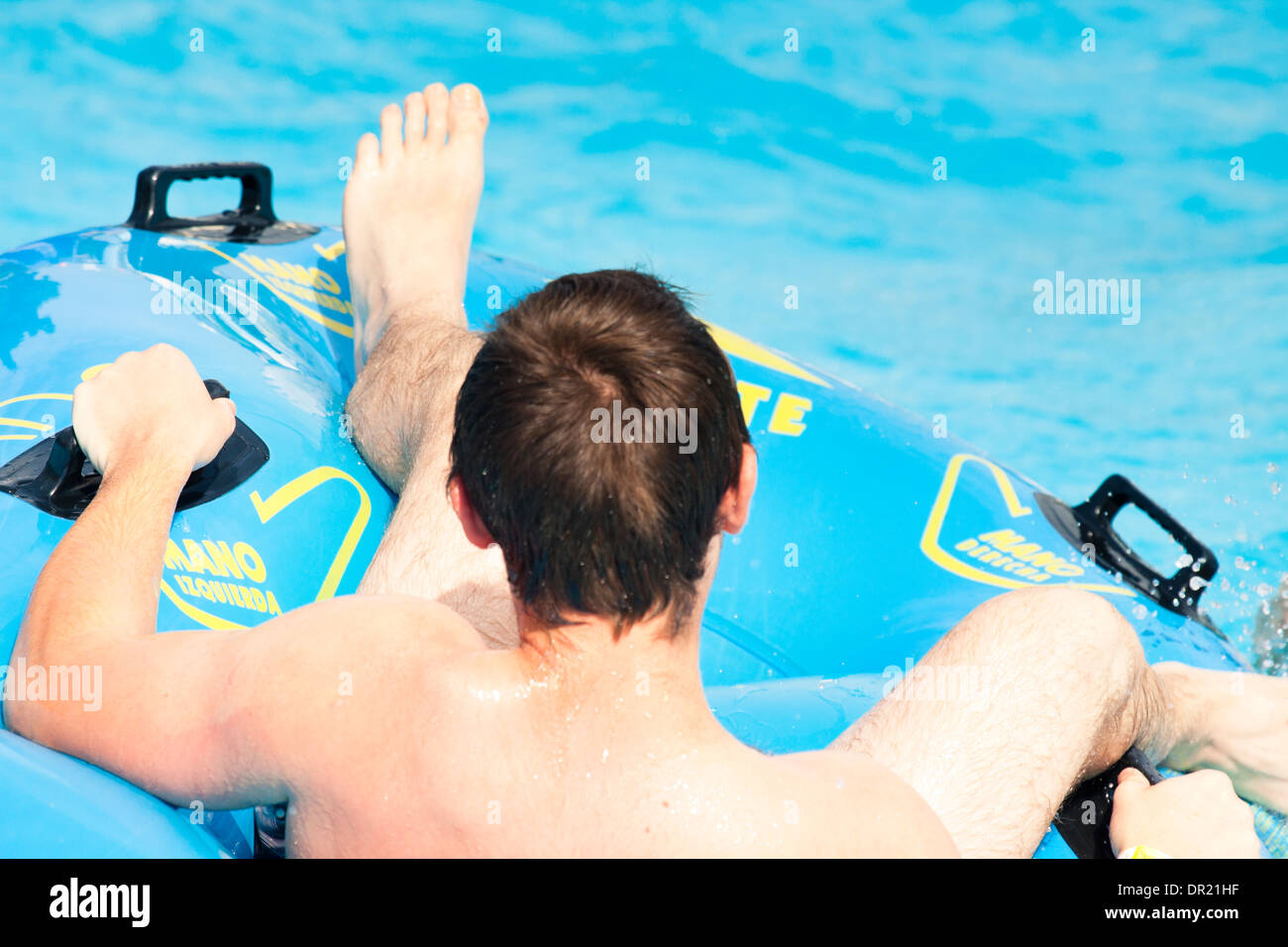 Giovane uomo su anello di gomma lo scorrimento di acqua a Aqua park. Foto Stock