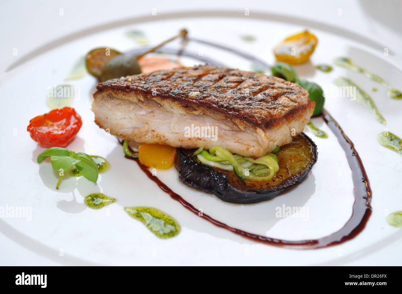 Pietra di Steamed bass con le melanzane, zucchine, peperoni, nero olio di oliva pesto & servita al Coq d'Argent, raffinati pranzi Francesi Londra Foto Stock