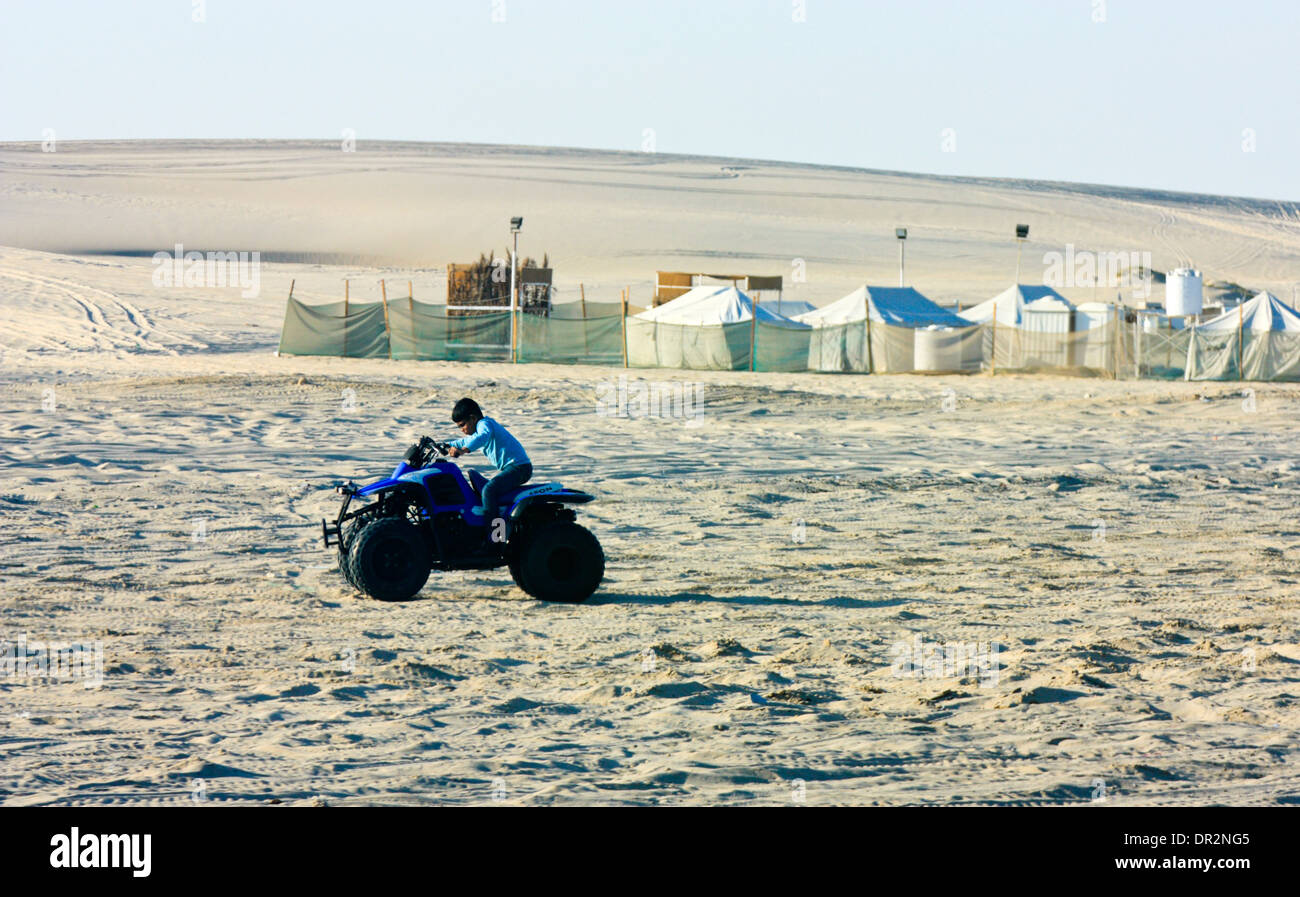 Ragazzo in sella a una Quad-Bike nel deserto, Sealine Beach, in Qatar Foto Stock