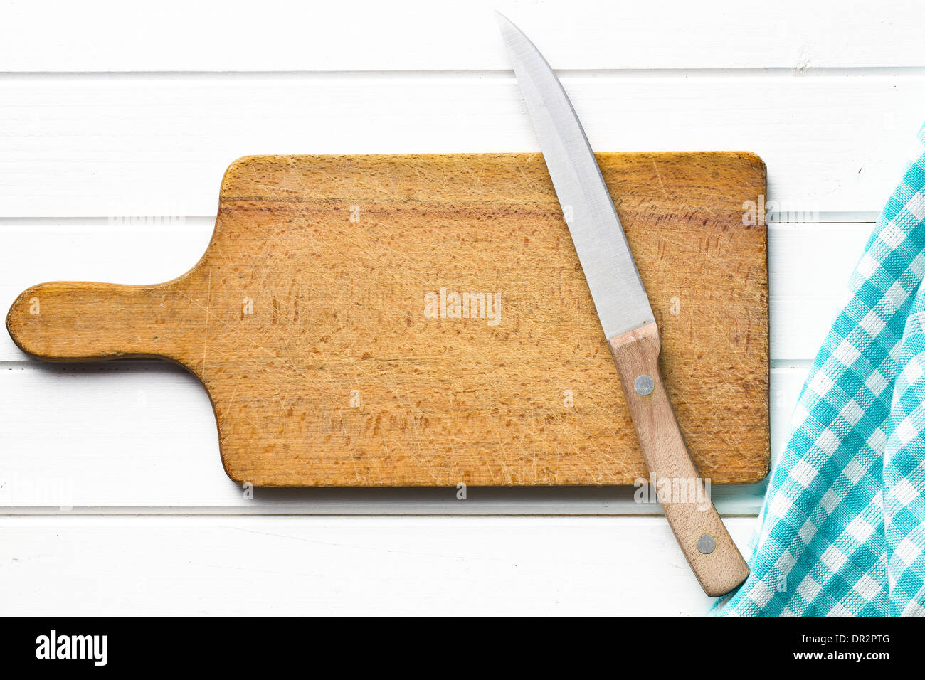 Vista superiore del bordo di taglio con il coltello su bianco tavolo in legno Foto Stock