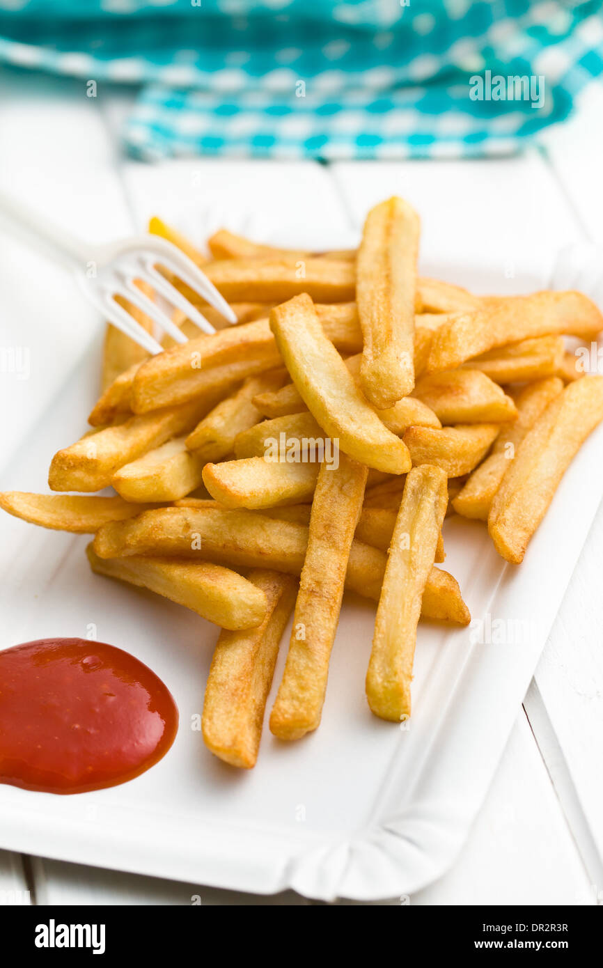 Patate fritte con ketchup sul piatto di carta bianco sul tavolo di legno Foto Stock
