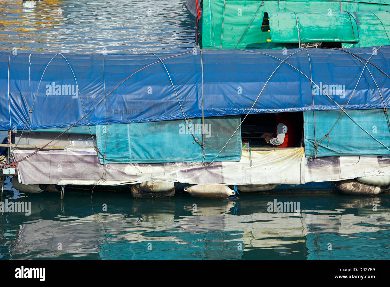 Uomo si siede in casa sua barca in Causeway Bay Typhoon Shelter, Hong Kong. Foto Stock