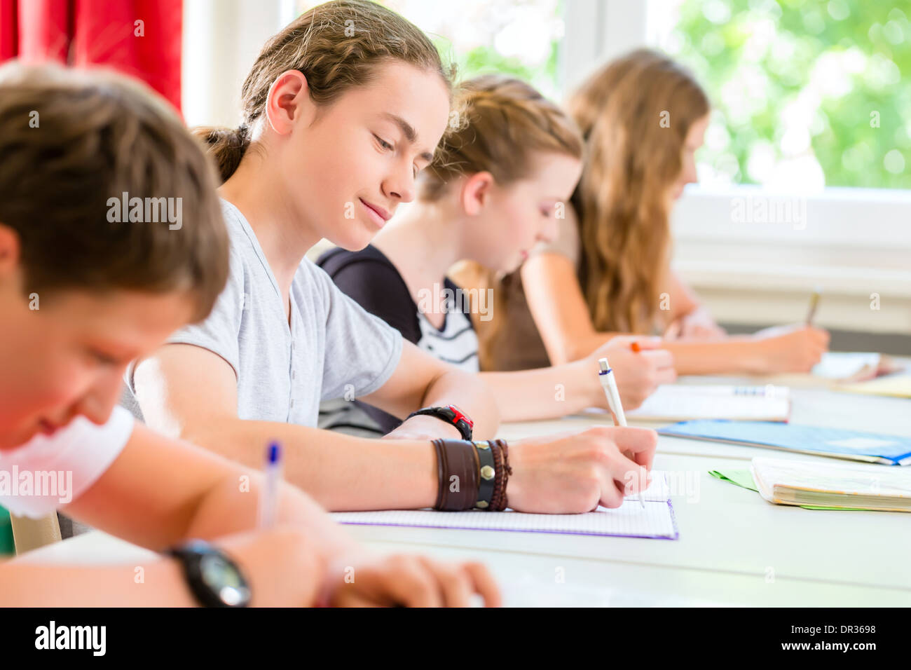 Studenti o alunni della classe scolastica di scrivere un test per l'esame in aula di concentrare il loro lavoro Foto Stock