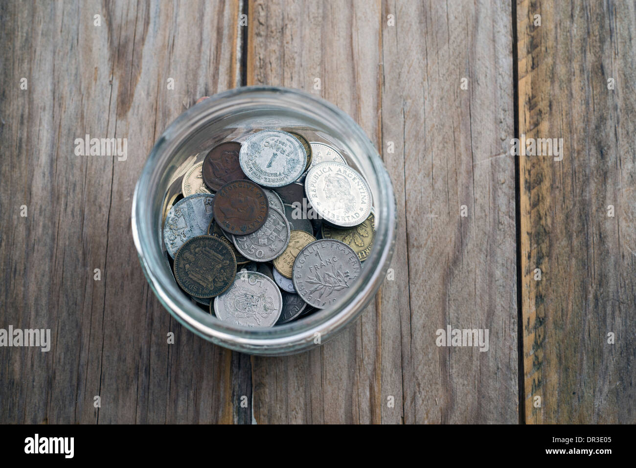 Collezione di monete in vetro vaso di risparmio su un tavolo di legno Foto Stock