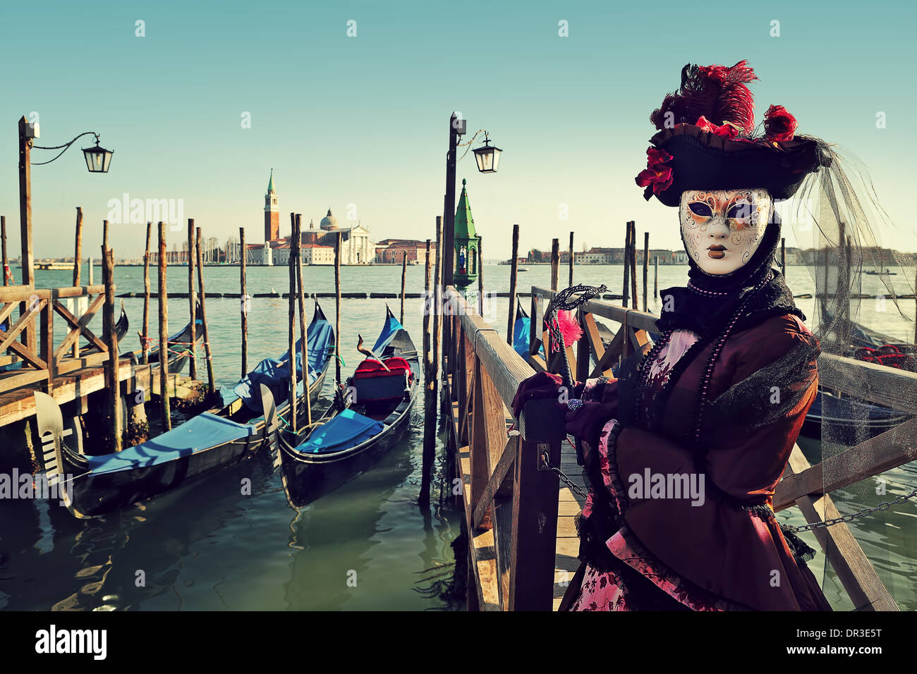 Il partecipante non identificato in maschera e costume sullo sfondo del Canal Grande e San Giorgio Maggiore a Venezia. Foto Stock