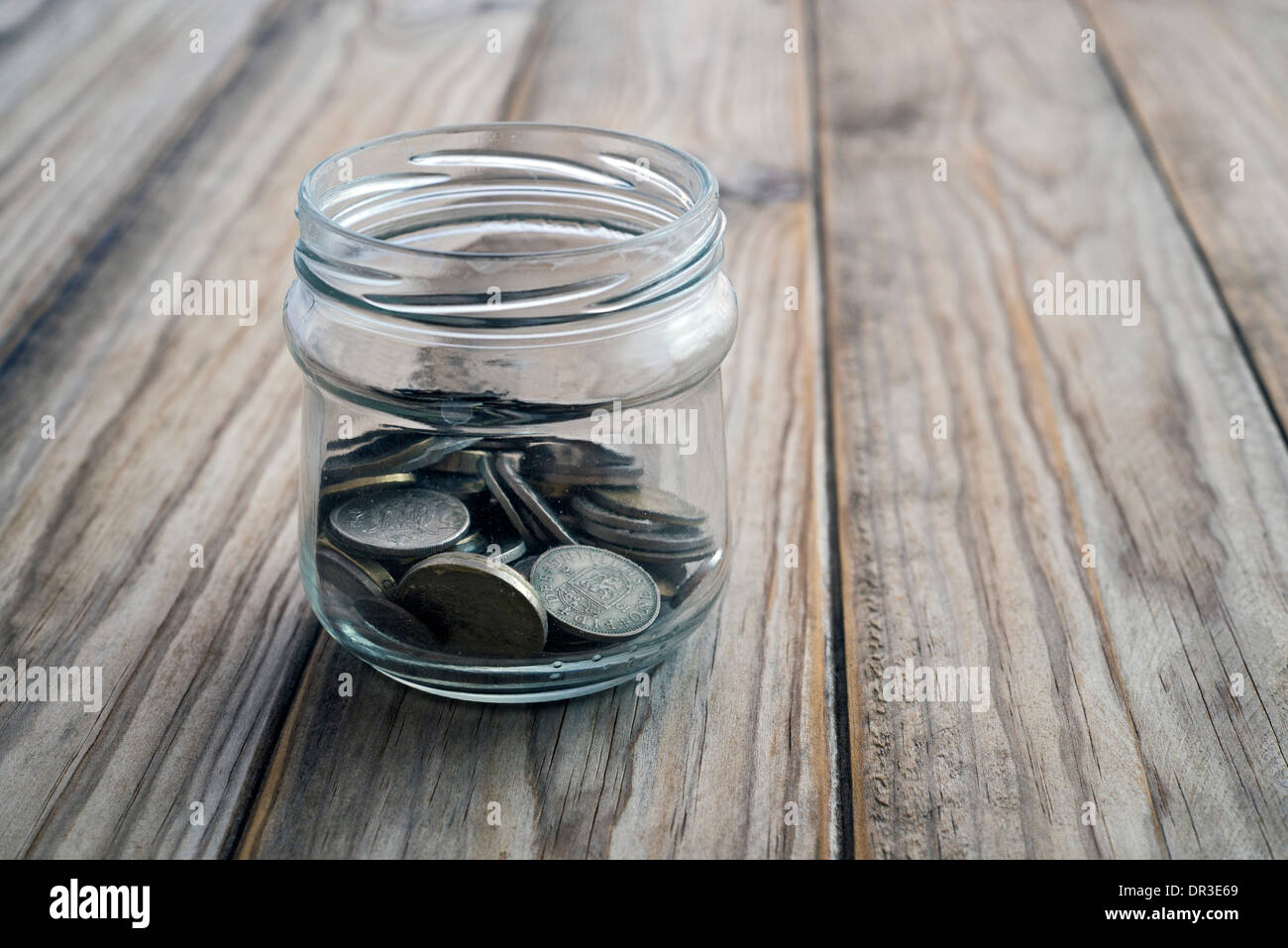 Collezione di monete in vetro vaso di risparmio su un tavolo di legno Foto Stock