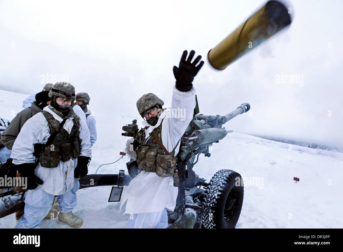Stati Uniti Soldato dell'esercito lancia un speso 105mm obice shell durante un live-fire esercitazione in Alaska Foto Stock