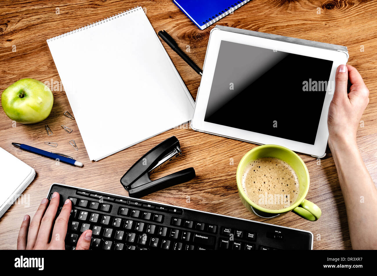 Compressa con una schermata vuota vicino a una penna e tazza verde e Apple Foto Stock