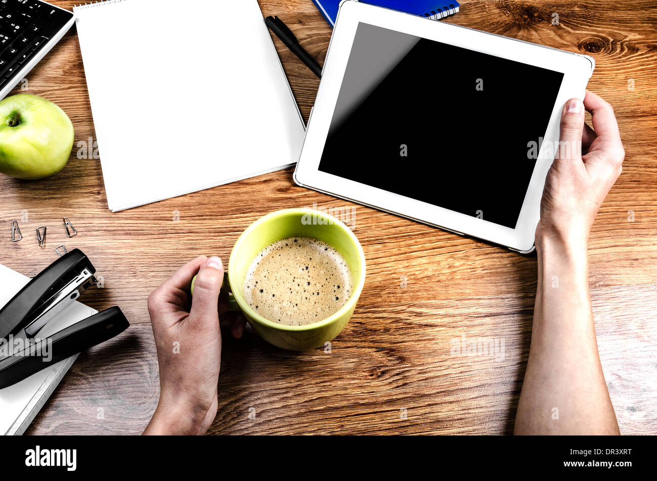 Compressa con una schermata vuota in mano vicino ad una penna e cup Foto Stock