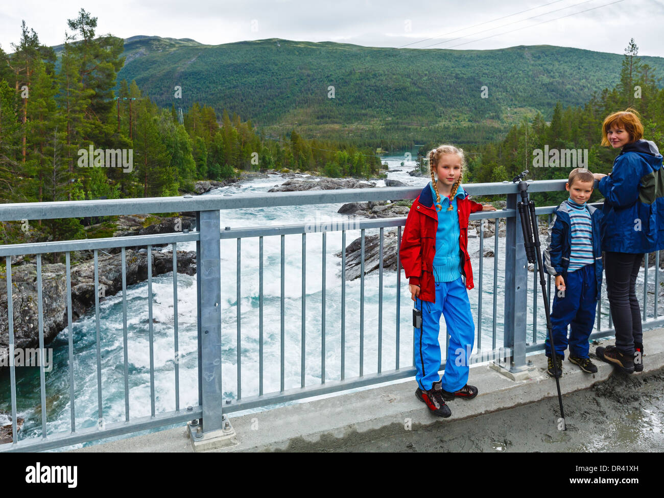 Madre con i bambini sul ponte vicino al fiume di montagna cascate(Ottafossen, Norge ) Foto Stock