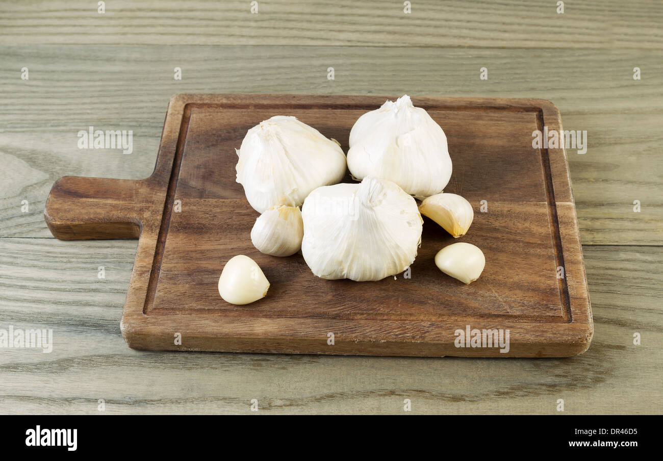 Foto orizzontale di fresco aglio crudo sul noce nero con bordo legno invecchiato sotto Foto Stock