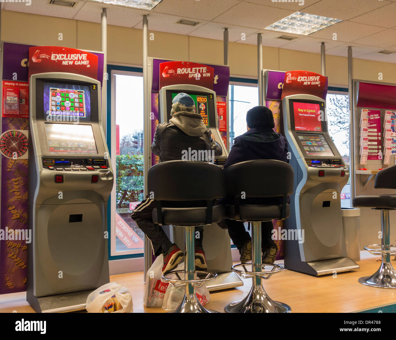 L uomo e la donna a quote fisse di macchine di gioco (FOBT fixed odds betting terminale) in Ladbrokes Betting shop. Regno Unito Foto Stock