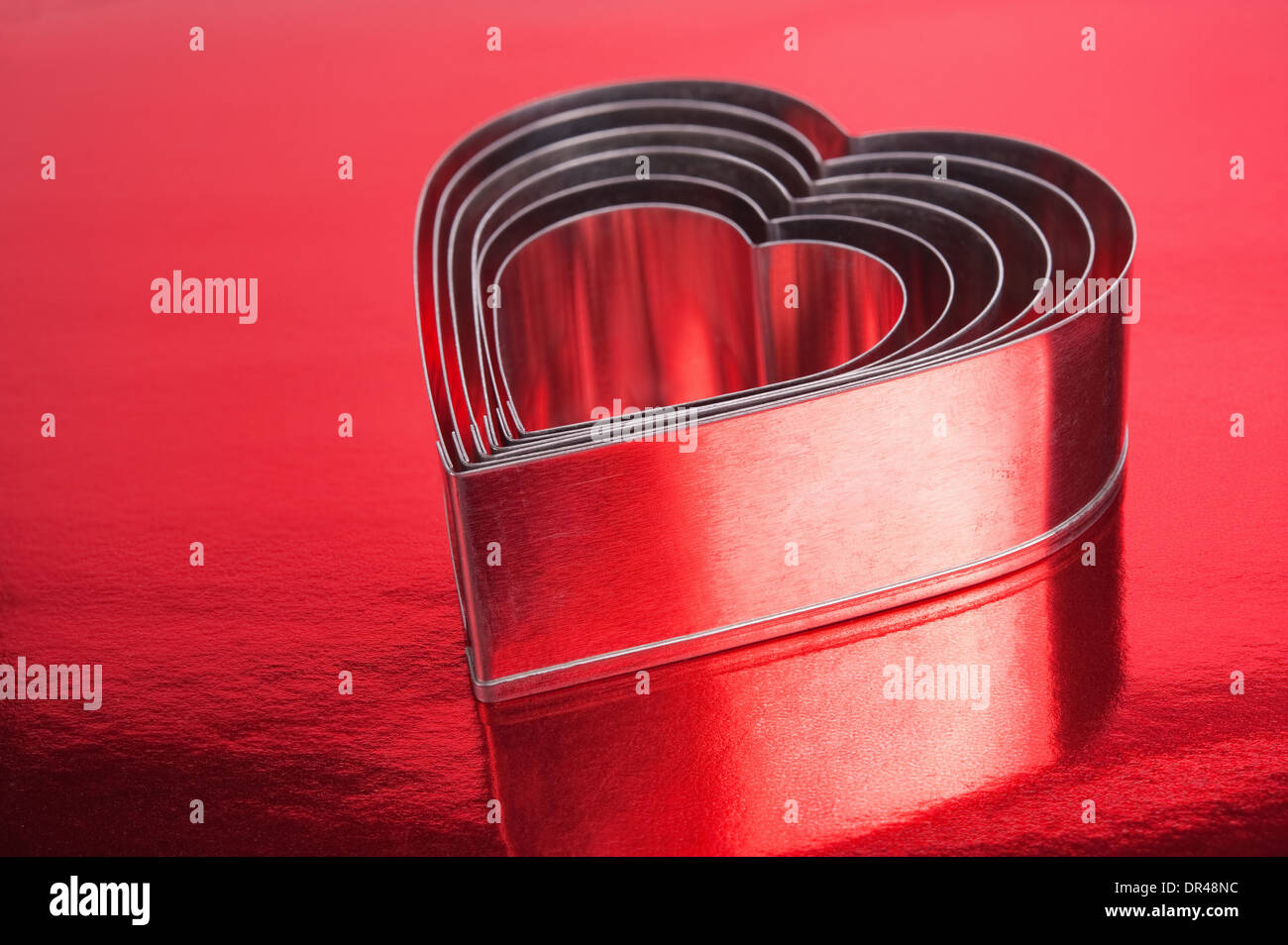 Alcuni di metallo a forma di cuore su sfondo rosso.Shallow DOF Foto Stock