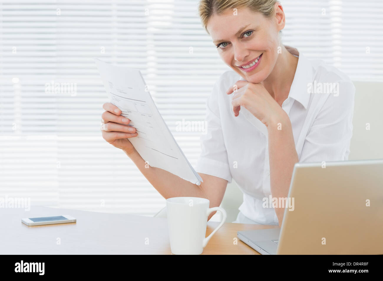 Imprenditrice con il computer portatile e il documento alla scrivania Foto Stock