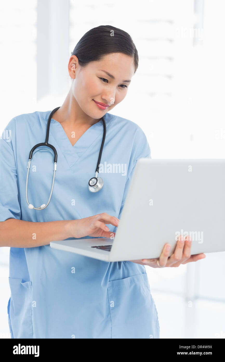 Concentrato chirurgo femmina usando un computer portatile Foto Stock