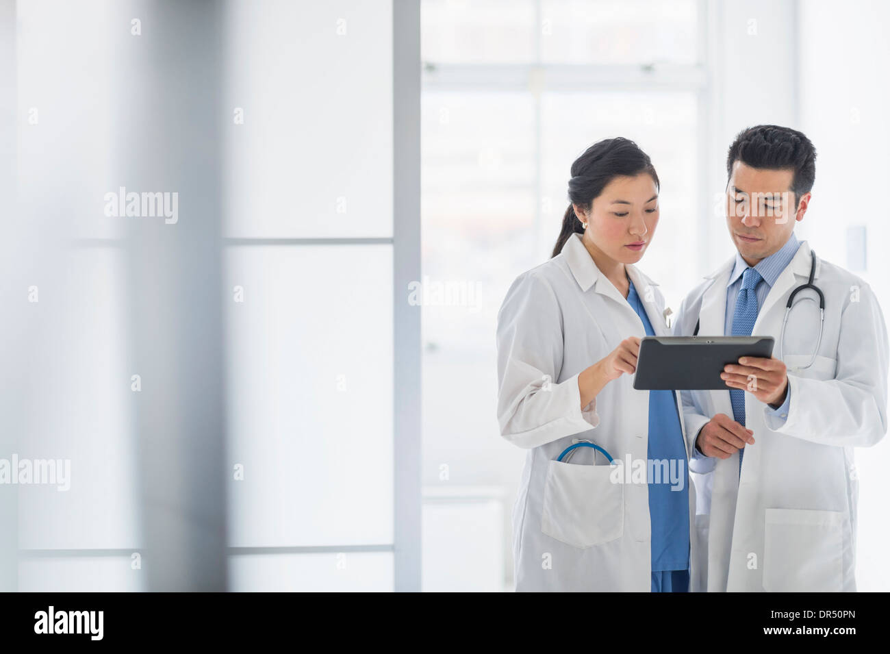 I medici utilizzando digitale compressa nel corridoio di ospedale Foto Stock