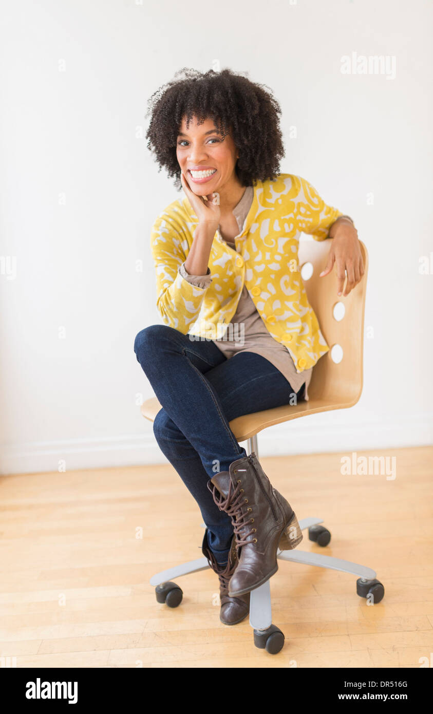 African American donna seduta in sedia ufficio Foto Stock