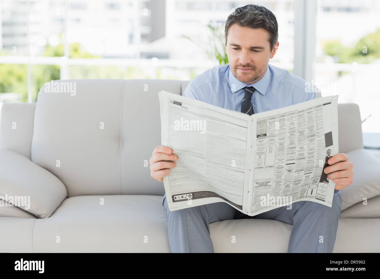 Ben vestito uomo quotidiano di lettura a casa Foto Stock