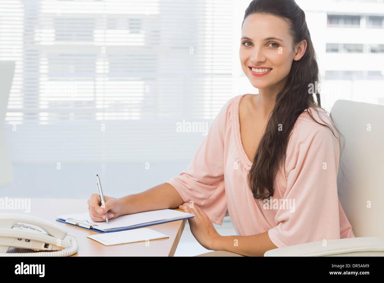 Imprenditrice iscritto negli appunti in un ufficio luminoso Foto Stock