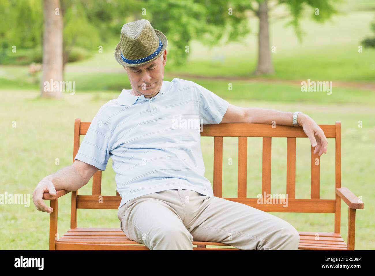 Senior rilassato uomo su una panchina in posizione di parcheggio Foto Stock