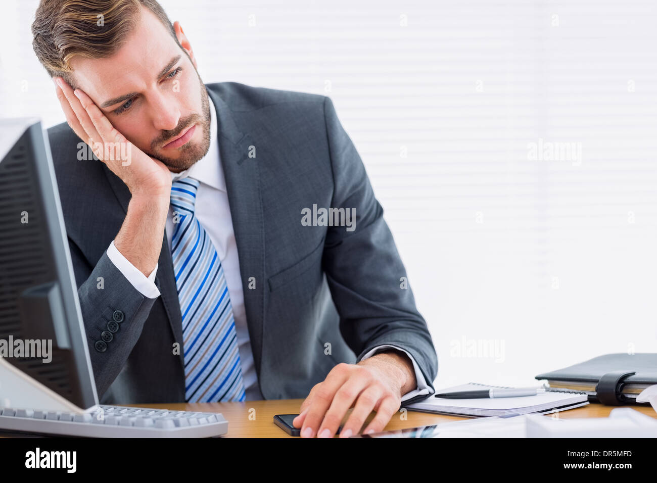 Imprenditore pensieroso seduto alla scrivania in ufficio Foto Stock