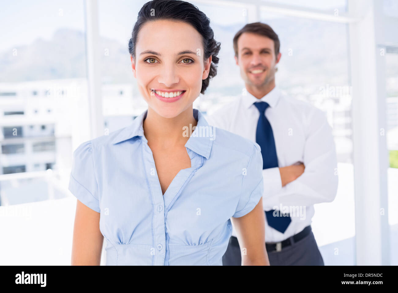 Imprenditrice sorridente con il collega di sesso maschile in background Foto Stock