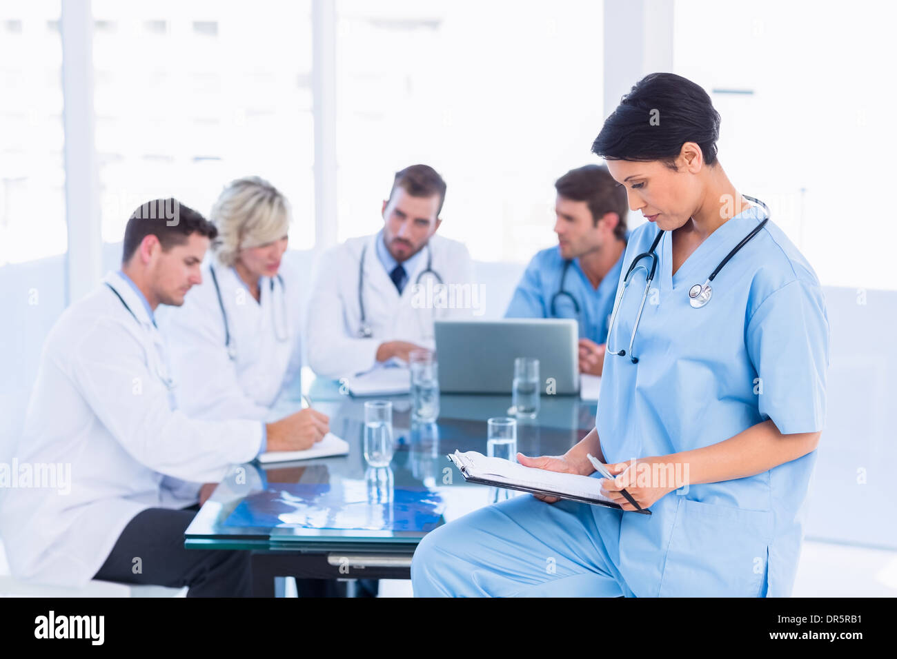 Chirurgo femmina guardando i rapporti con i colleghi in riunione Foto Stock