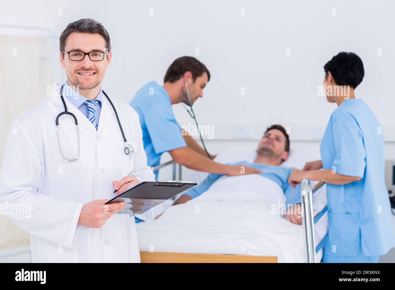 Medico tenendo i rapporti con il paziente ed il chirurgo in background Foto Stock