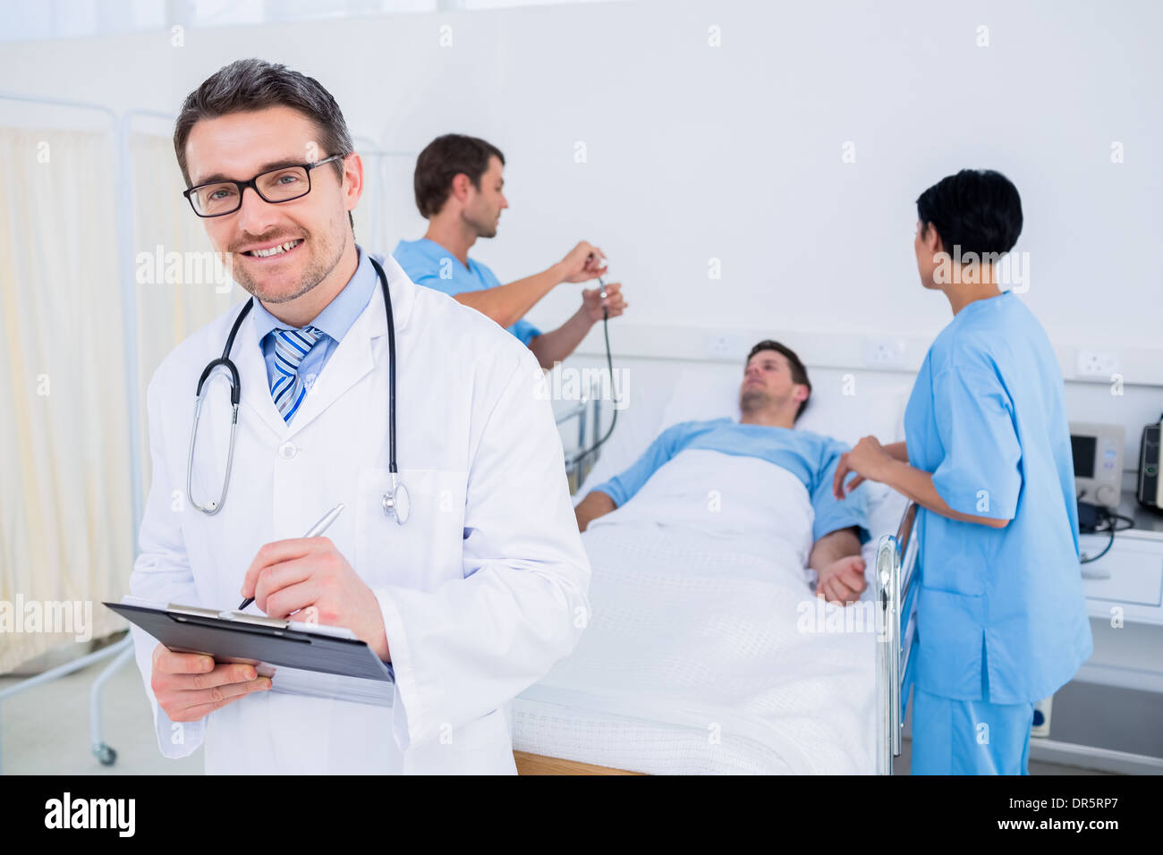 Medico scrivere rapporti con paziente e chirurghi in background Foto Stock