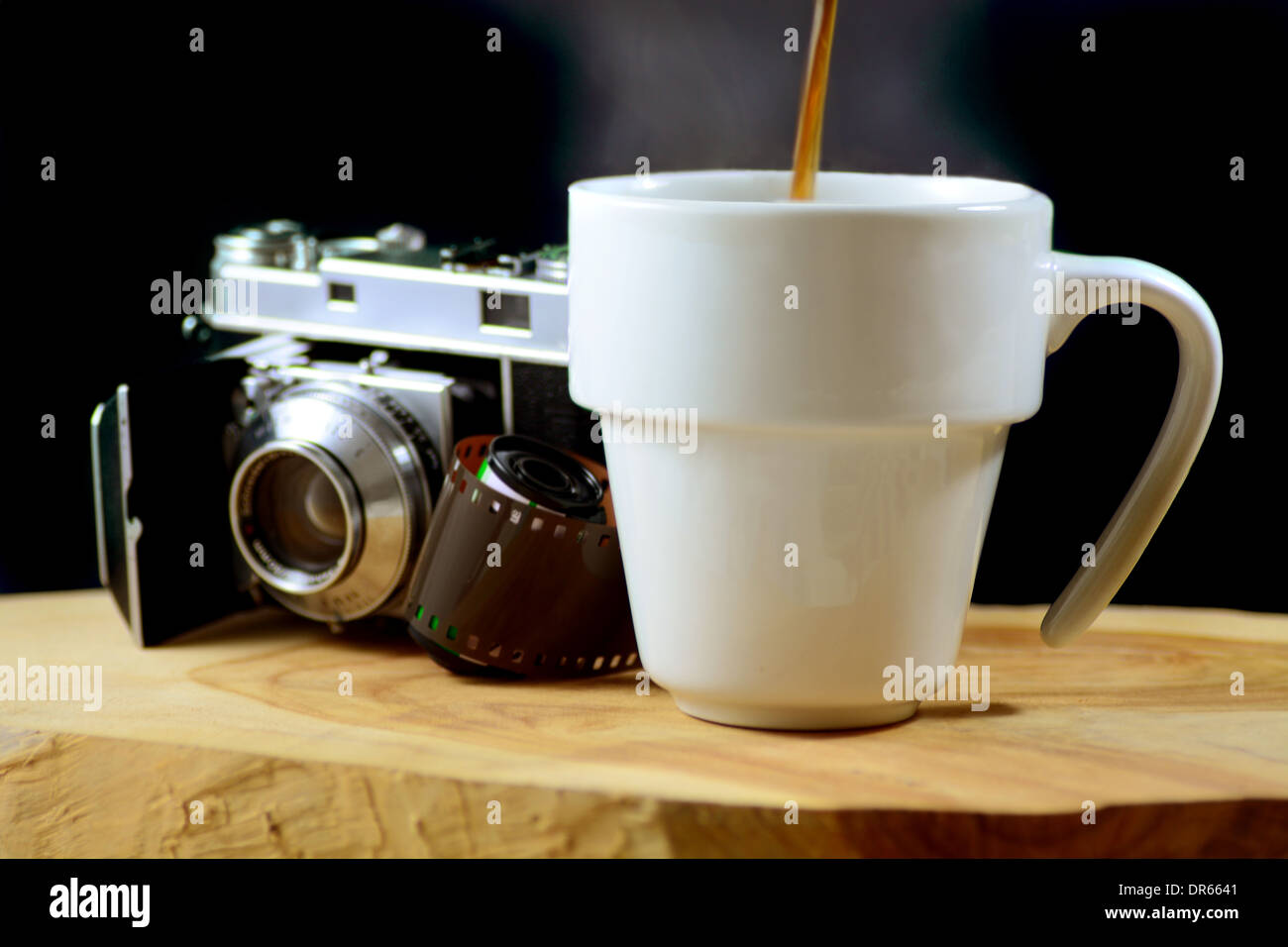Ripresa macro di una fumante tazza di caffè con una telecamera analogica e il rotolo di pellicola in background Foto Stock