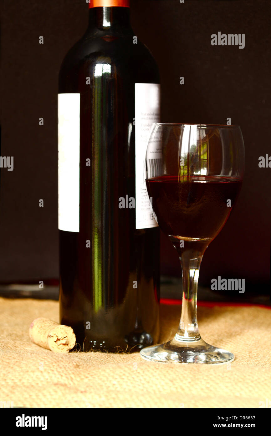 Bottiglia di vino rosso e un bicchiere di vino su una impostazione paese Foto Stock