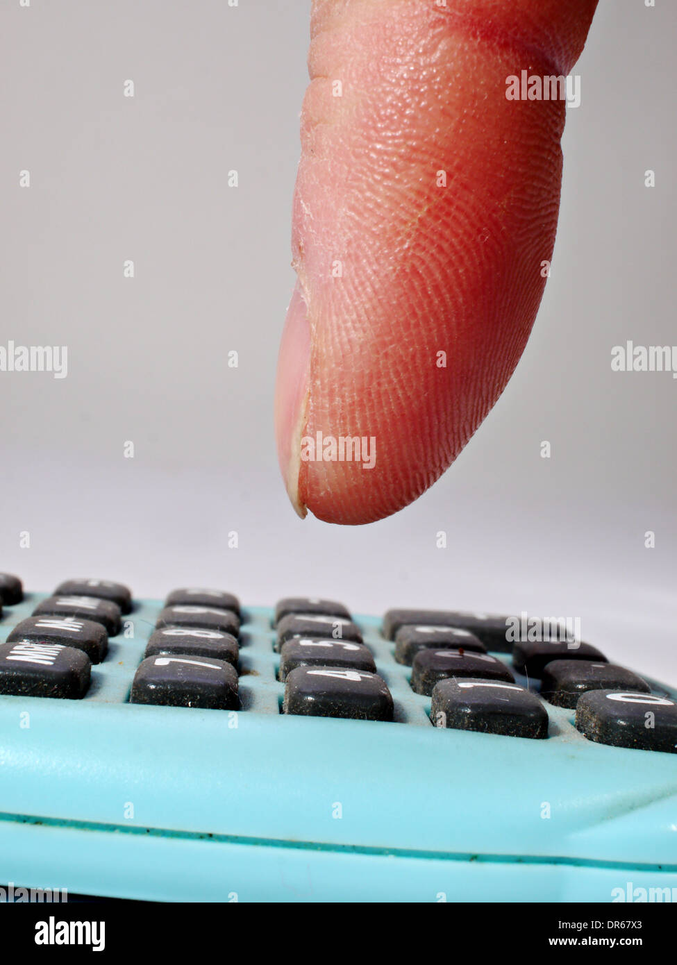 Un dito che sta per spingere un pulsante su una piccola calcolatrice Foto Stock
