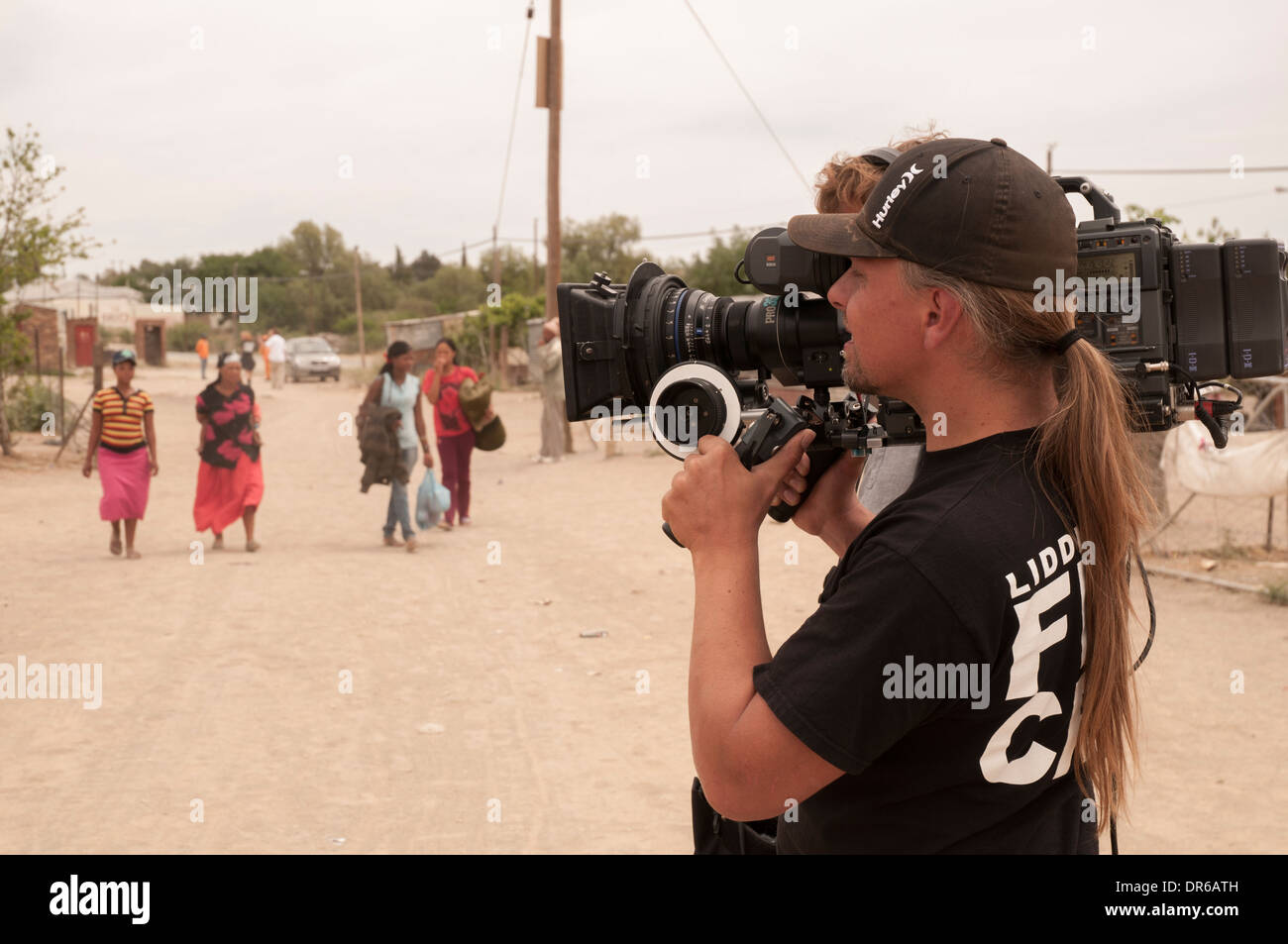 Cameraman consente di girare video in HD con un primo obiettivo in un polveroso e poveri città in Sud Africa settentrionale di Cape. Foto Stock