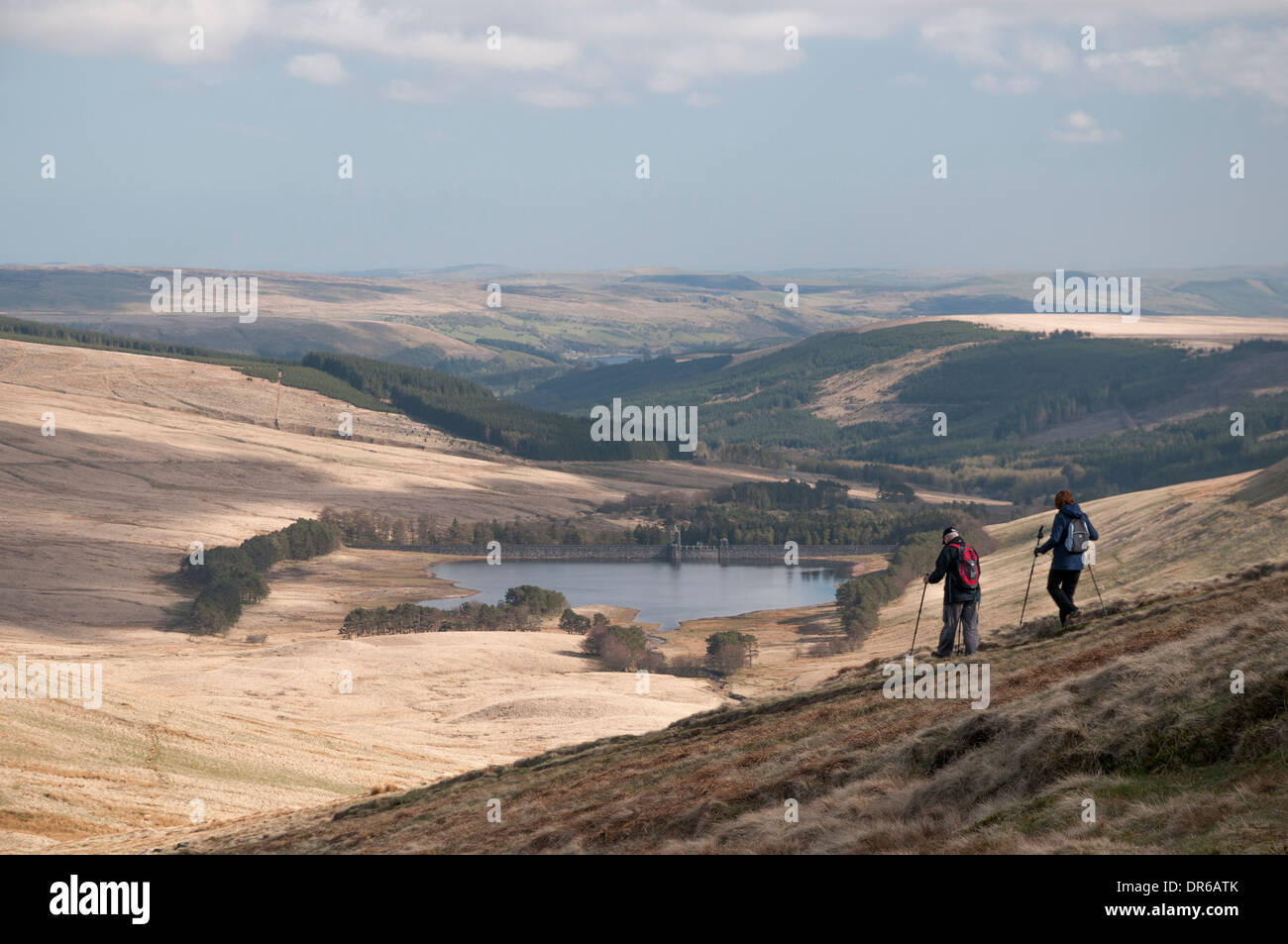 Coppia di anziani escursioni a piedi giù per la collina in Galles Brecon Beacons - Il serbatoio Neuadd passeggiata a ferro di cavallo. Foto Stock
