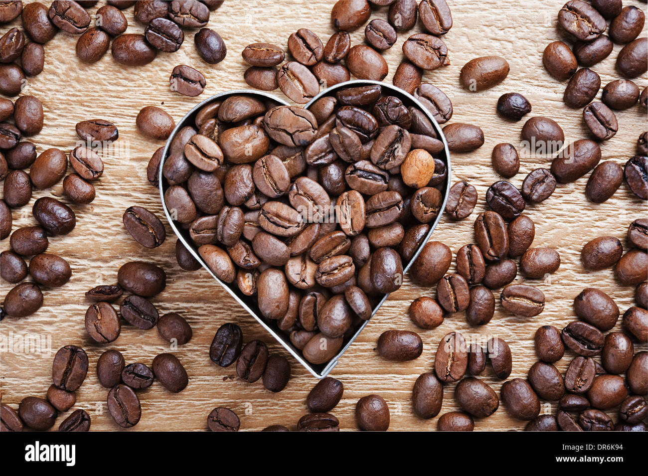 I chicchi di caffè come sfondo dal buon caffè torrefatto in grani con cuore di metallo a forma di telaio Foto Stock