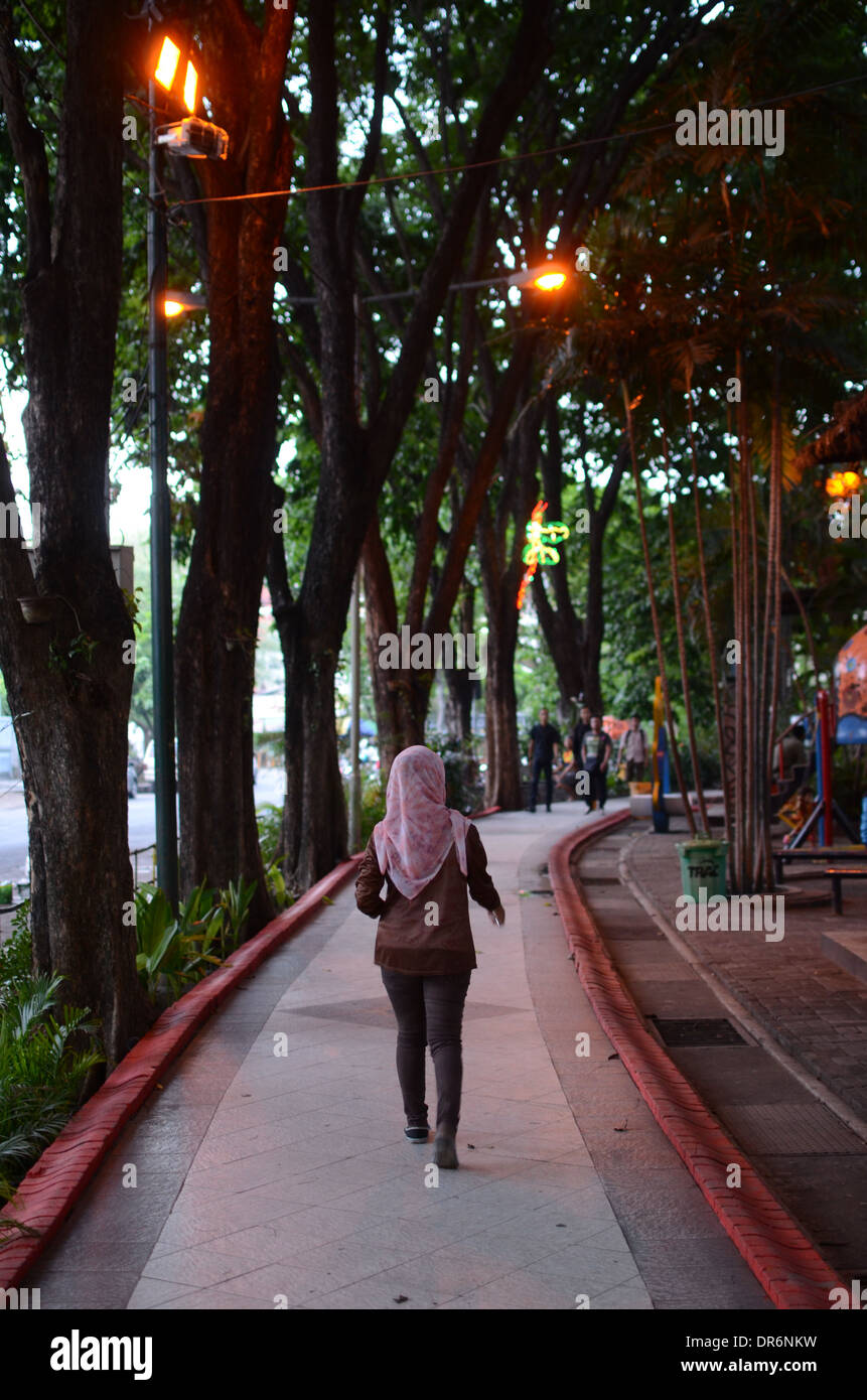 Residenti a piedi lungo un sentiero all'ombra di alberi in Bungkul Park - Il miglior parco cittadino in Asia Foto Stock