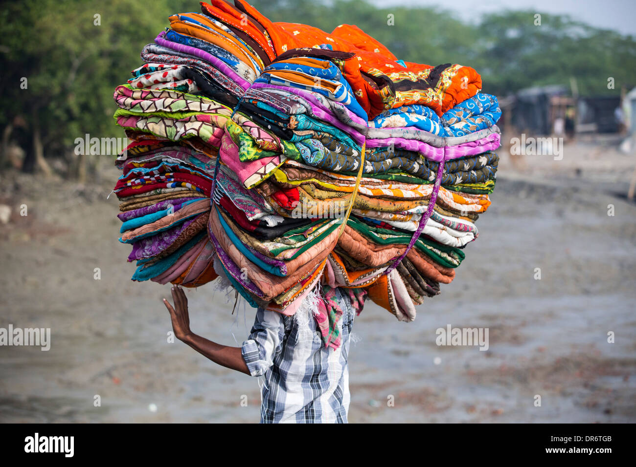 Un uomo che porta i tessuti in Sunderbans, un basso area del delta del Gange in India Orientale, che è molto vulnerabile a mare Foto Stock