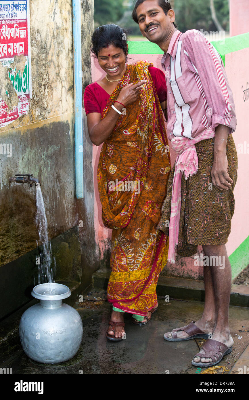 Gli abitanti di un villaggio in una remota isola nel Sunderbans, una bassa area sdraiato, vulnerabile di innalzamento del livello del mare, l'India, la raccolta di acqua da un pozzo di trivellazione e. Foto Stock