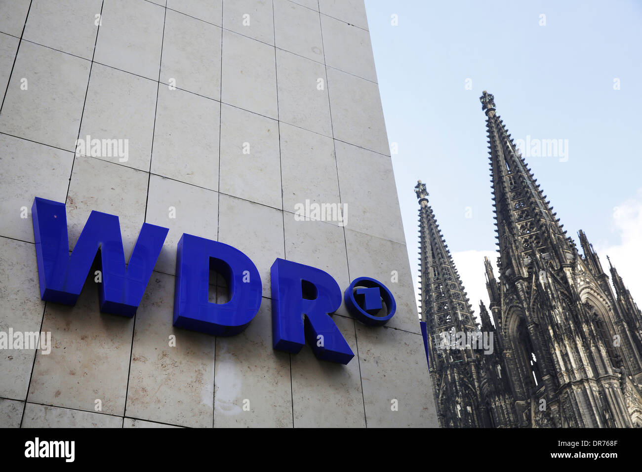 La facciata della casa con il logo della WDR (Westdeutscher Rundfunk, West German Broadcasting), parte della cattedrale di Colonia a sfondo Foto Stock