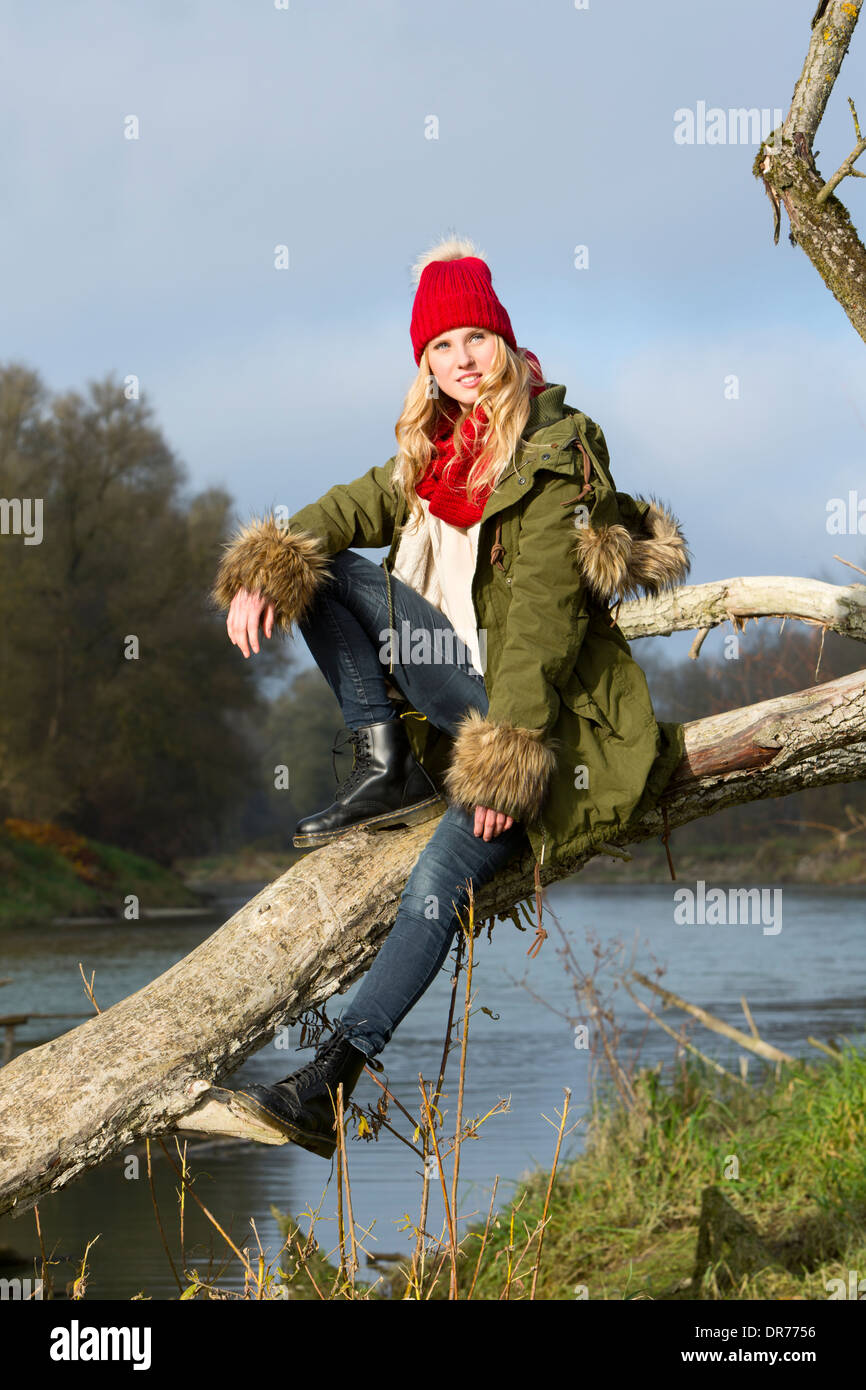 Giovane donna seduta al tronco di albero Foto Stock