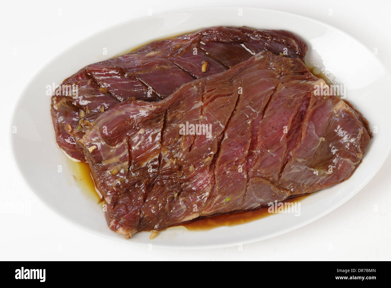 Due pezzi di fianco la bistecca o 'London cuocere' marinaded e poggiante su una piastra. Foto Stock