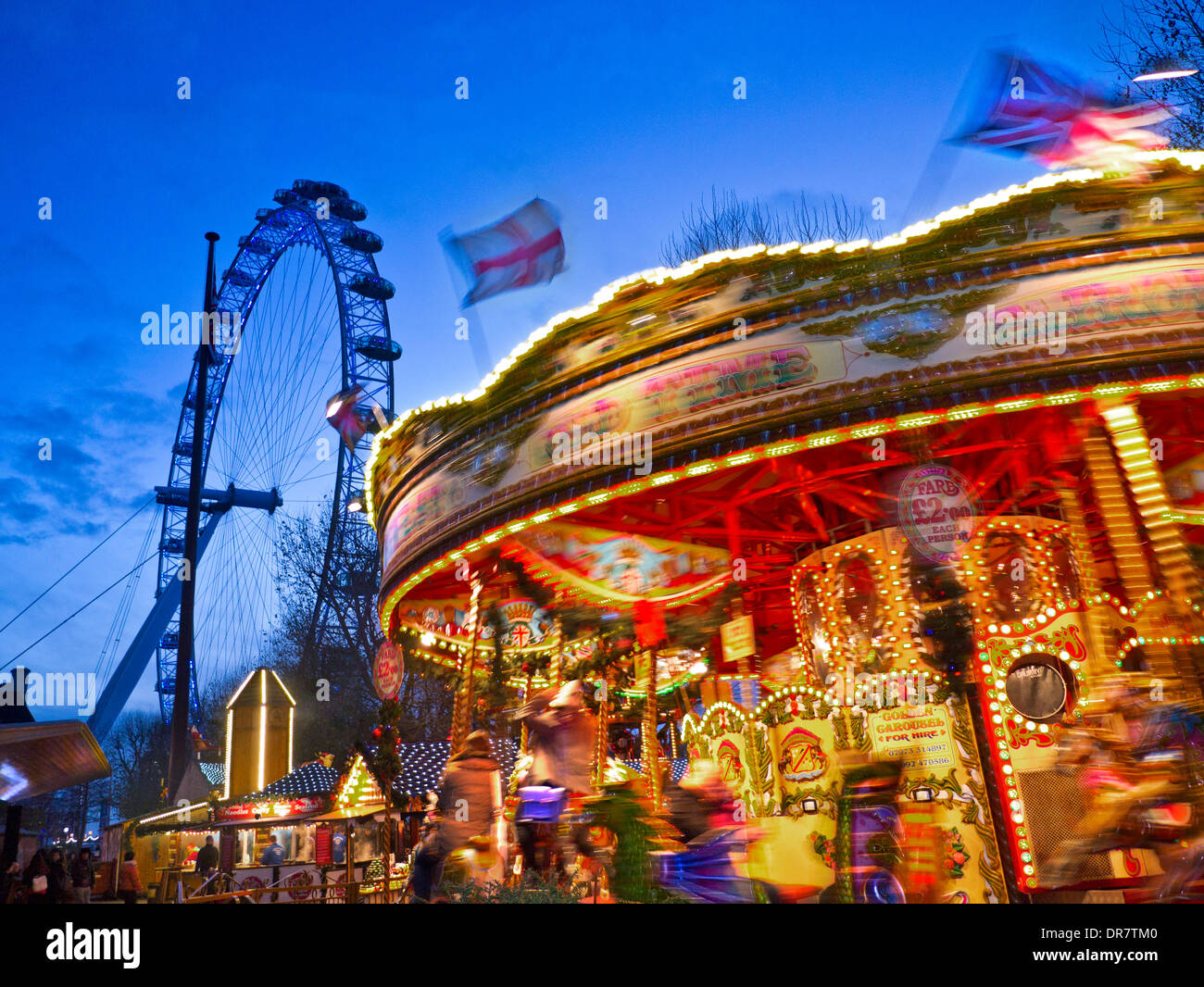 Parco di divertimenti invernali ride con il London Eye dietro al crepuscolo Jubilee Gardens South Bank di Londra Inghilterra Foto Stock