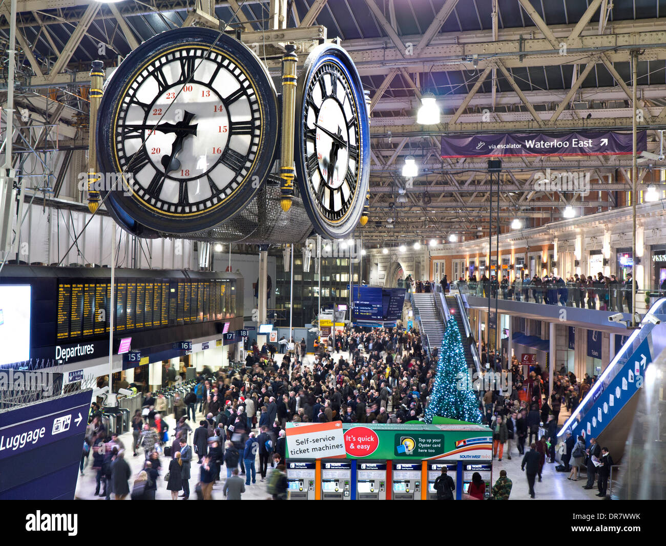 Vista in elevazione del concourse occupato presso la stazione di Waterloo con clock a 6,45 pm in primo piano a Natale London SE1 Foto Stock