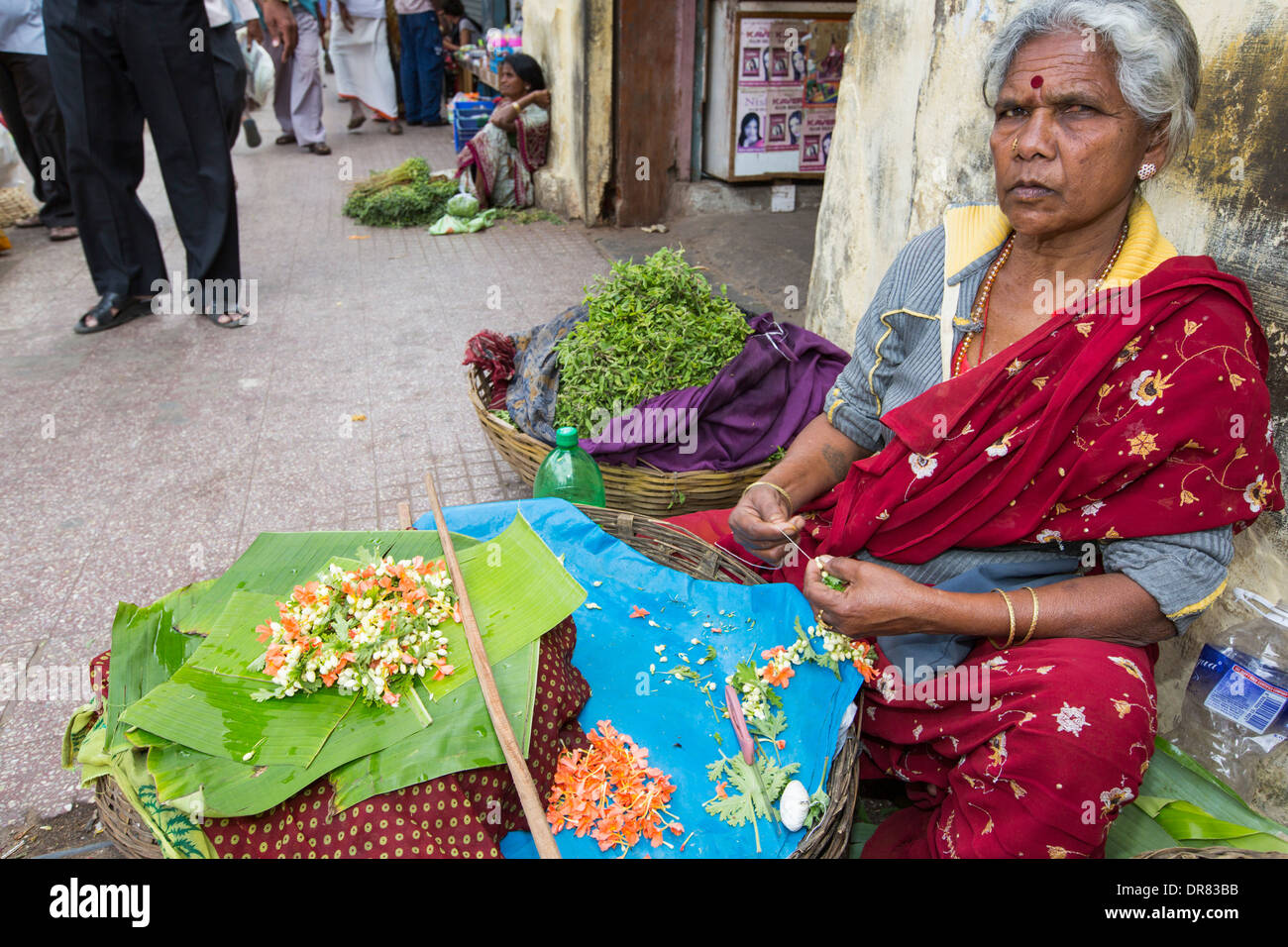 Una donna che fa floral decorazioni capelli ad una strada del mercato di Mysore, India. Foto Stock